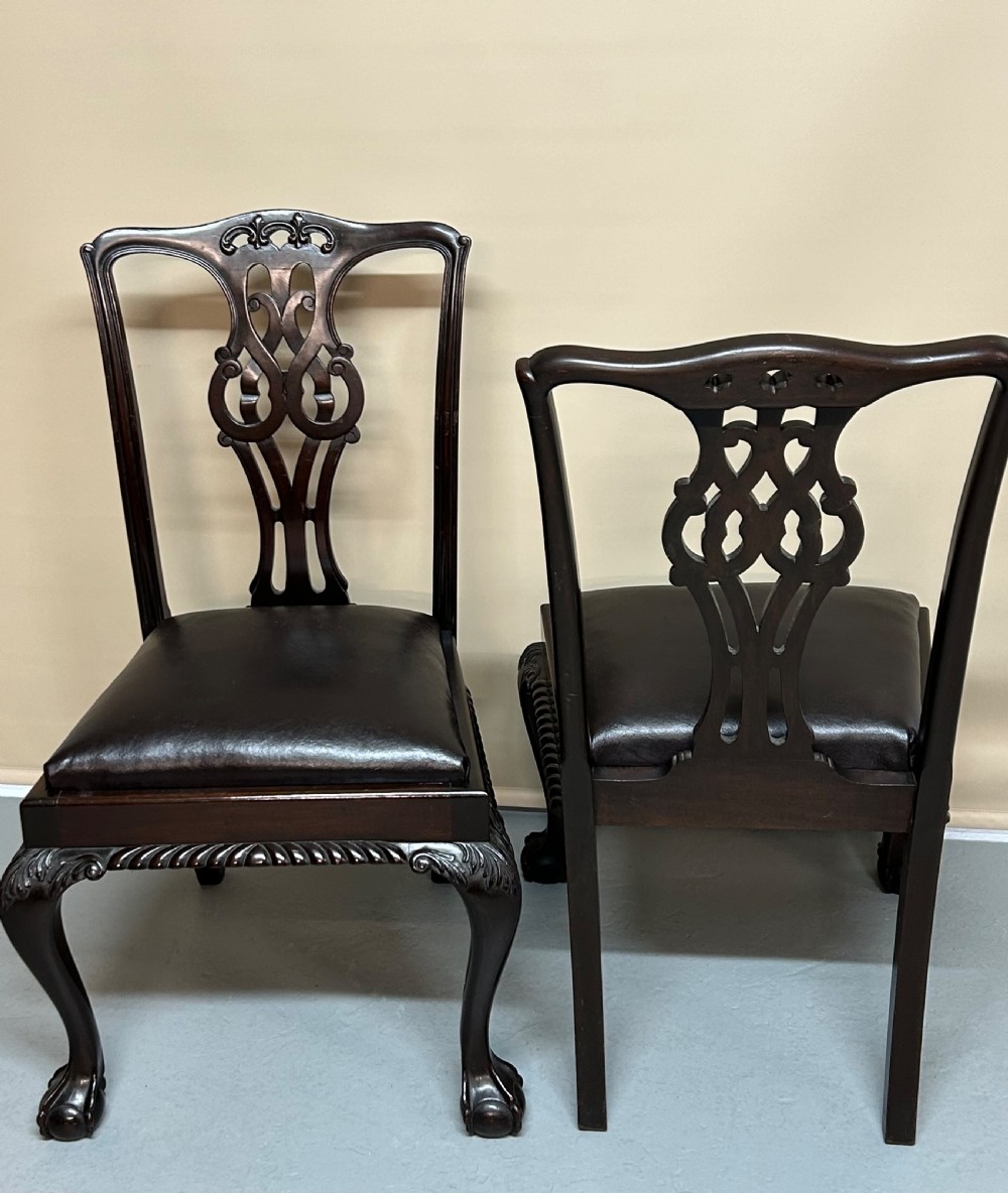 A set of six dark mahogany Chippendale style dining chairs featuring carved pierced back splats, dark leather seats, and front cabriole legs with ball and claw feet. View V