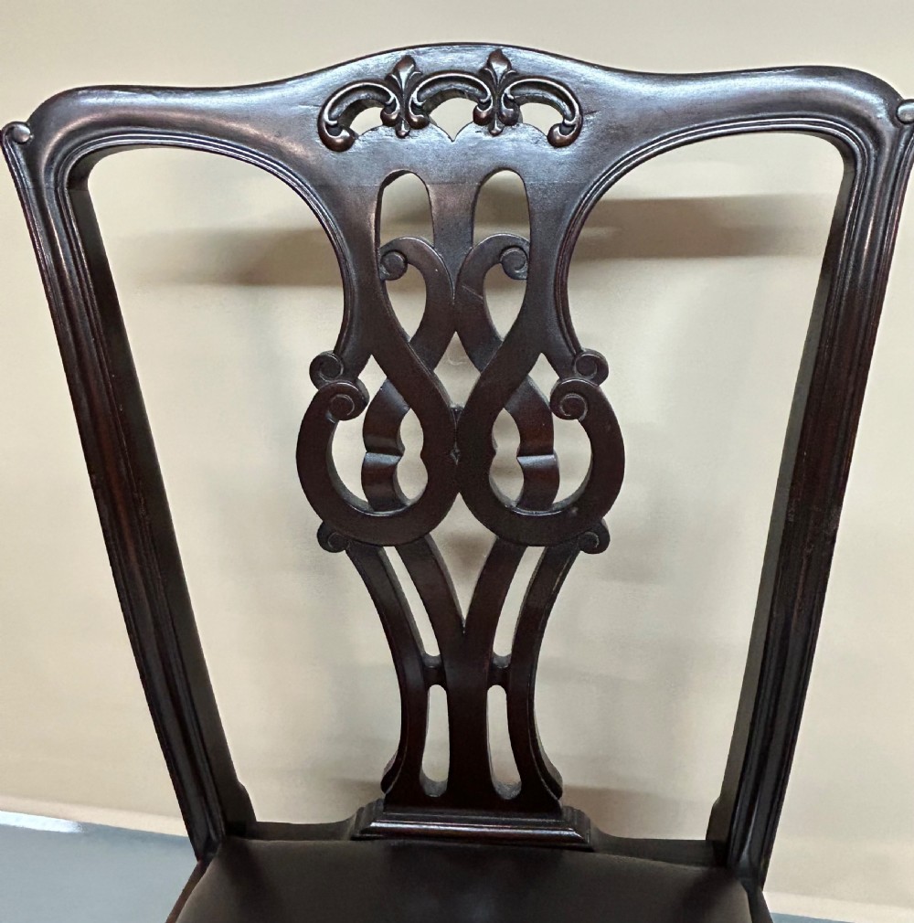 A set of six dark mahogany Chippendale style dining chairs featuring carved pierced back splats, dark leather seats, and front cabriole legs with ball and claw feet. View VI
