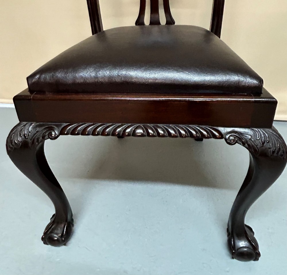 A set of six dark mahogany Chippendale style dining chairs featuring carved pierced back splats, dark leather seats, and front cabriole legs with ball and claw feet. View VII
