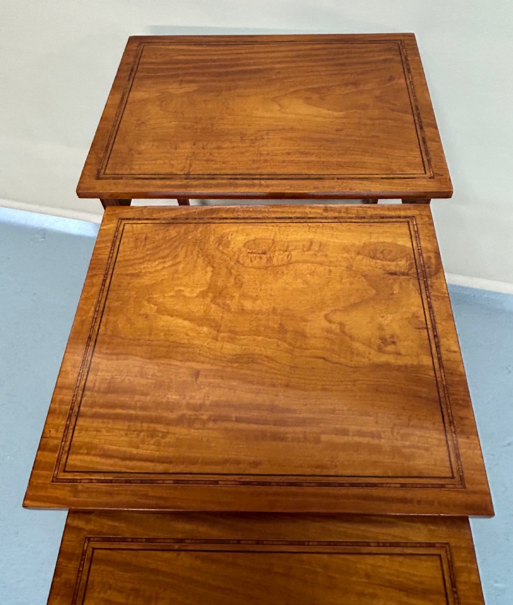 A set of four graduated wooden nesting tables featuring satinwood tops with dark inlaid borders and slim tapered square legs. View III