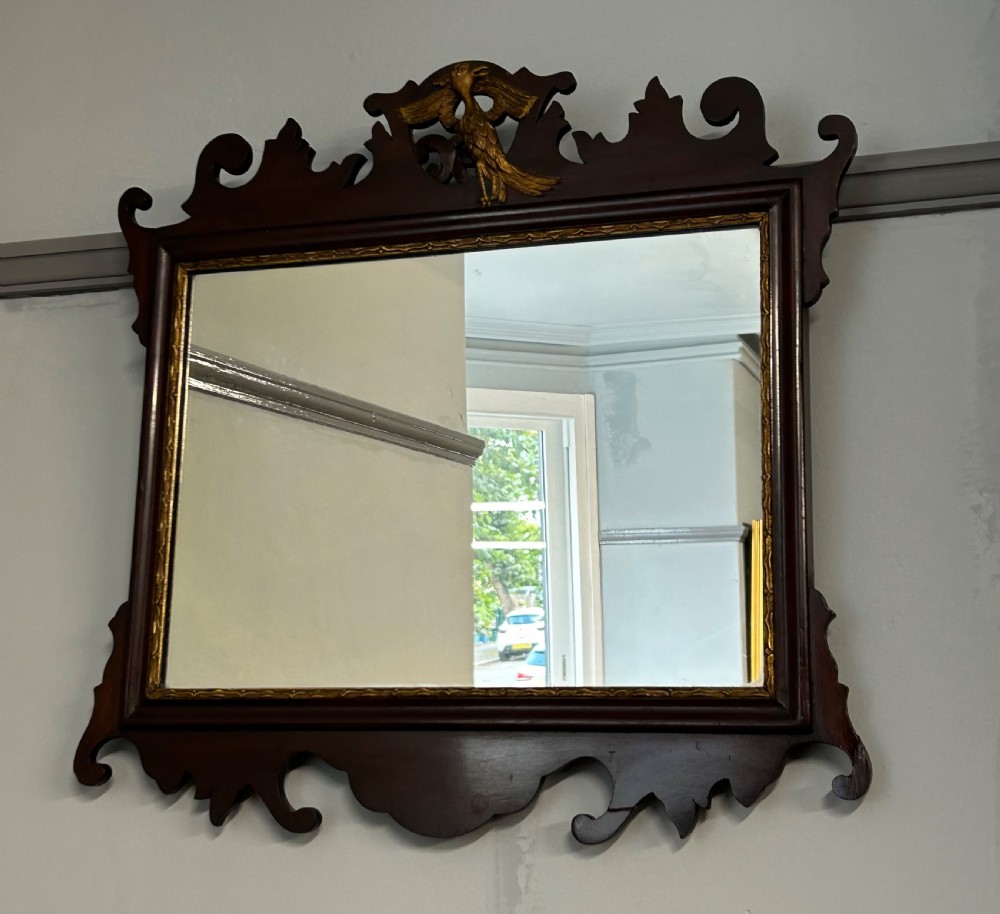 A rectangular Georgian style mahogany wall mirror featuring a scroll-cut fretwork frame topped with a gilded bird crest.