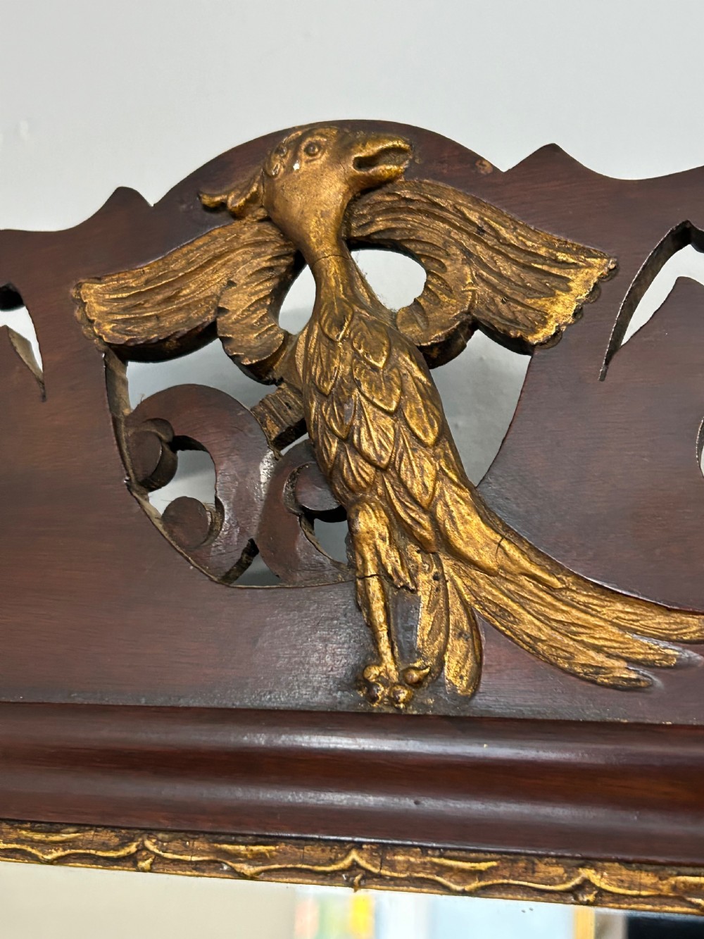 A rectangular Georgian style mahogany wall mirror featuring a scroll-cut fretwork frame topped with a gilded bird crest. View V