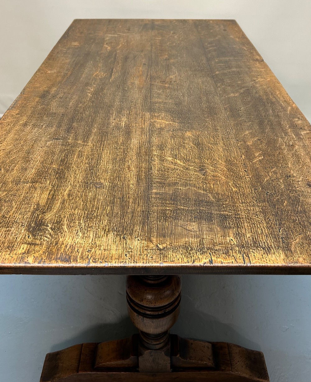 A solid oak refectory dining table featuring a rectangular top, heavy turned baluster legs, and a low central stretcher. View III