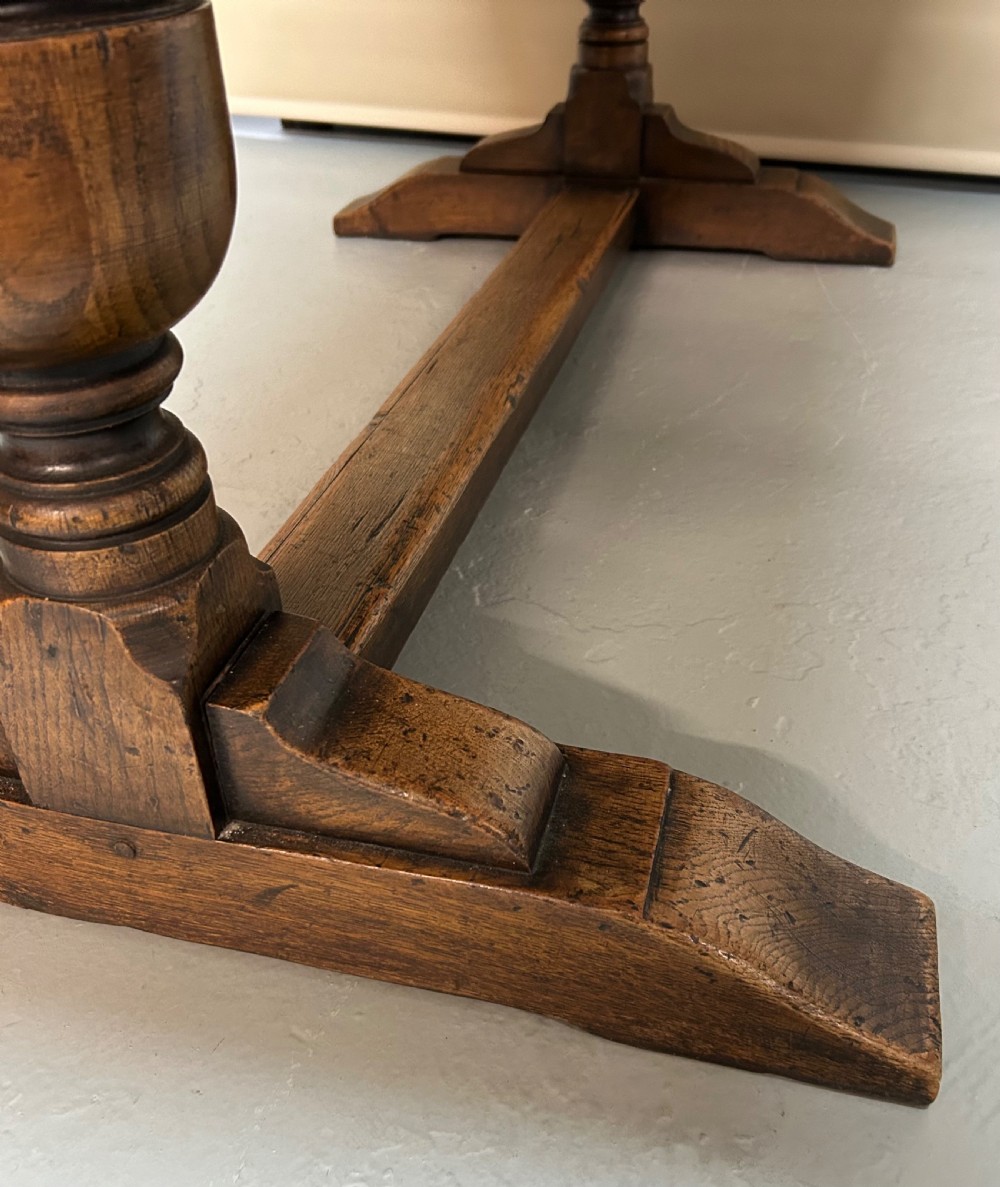 A solid oak refectory dining table featuring a rectangular top, heavy turned baluster legs, and a low central stretcher. View V