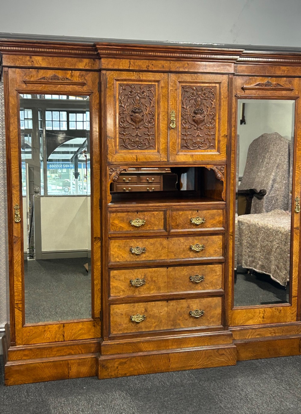 A large Victorian pollard oak breakout wardrobe featuring twin mirrored doors flanking a central carved cupboard above an open niche and five drawers with brass handles.