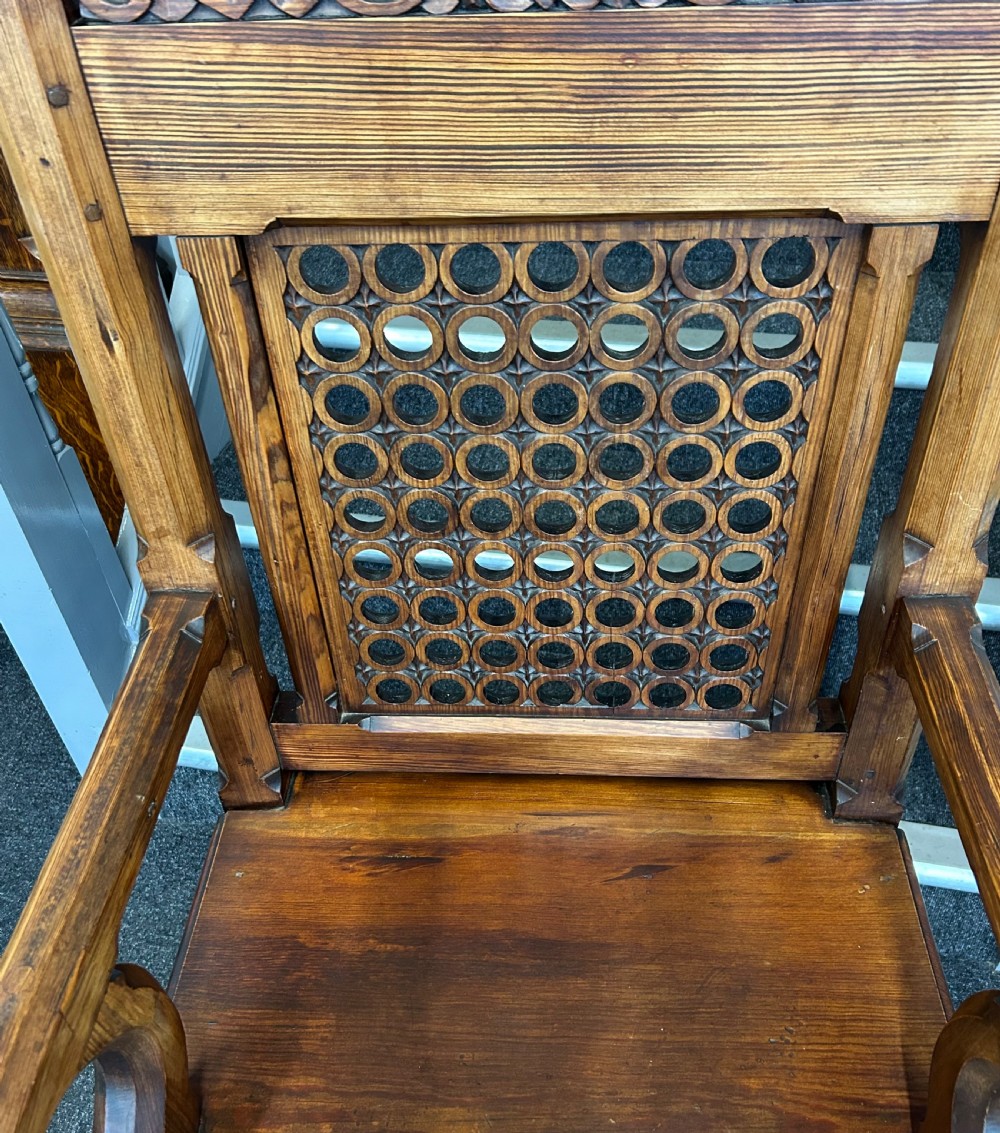 An antique Gothic Revival pitch pine throne armchair featuring a carved geometric crest, openwork lattice back panel, curved arms, and trefoil-pierced lower apron. View VI
