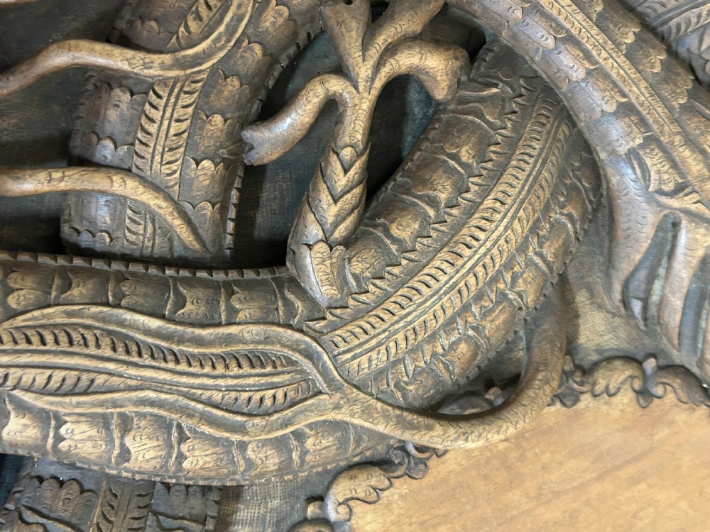 An octagonal wooden side table with high-relief carvings of dragons across the top surface and pierced base. View V