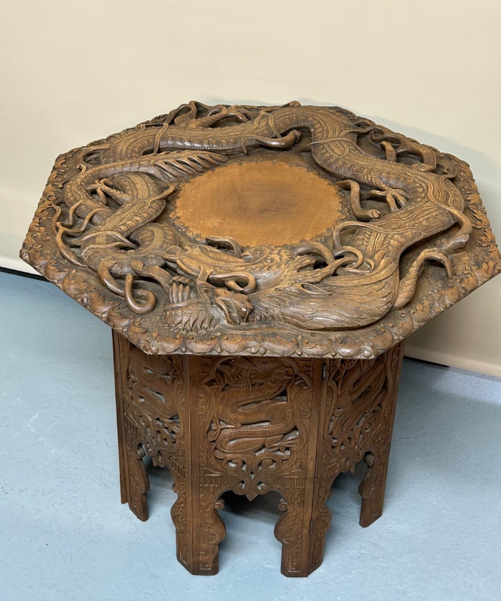An octagonal wooden side table with high-relief carvings of dragons across the top surface and pierced base. View VI