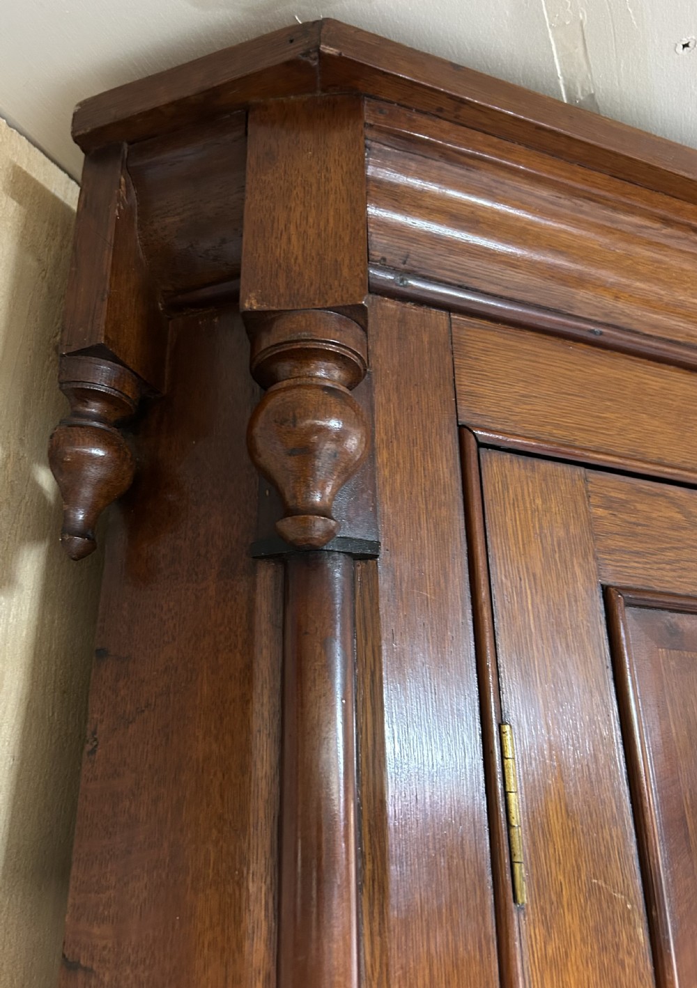 A tall freestanding antique Welsh oak corner cabinet with upper leaded glass doors, turned pendant drop mouldings, middle drawers, and lower panelled doors. View IV