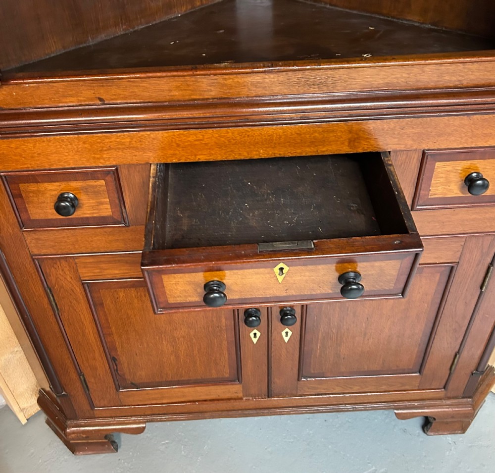 A tall freestanding antique Welsh oak corner cabinet with upper leaded glass doors, turned pendant drop mouldings, middle drawers, and lower panelled doors. View VII