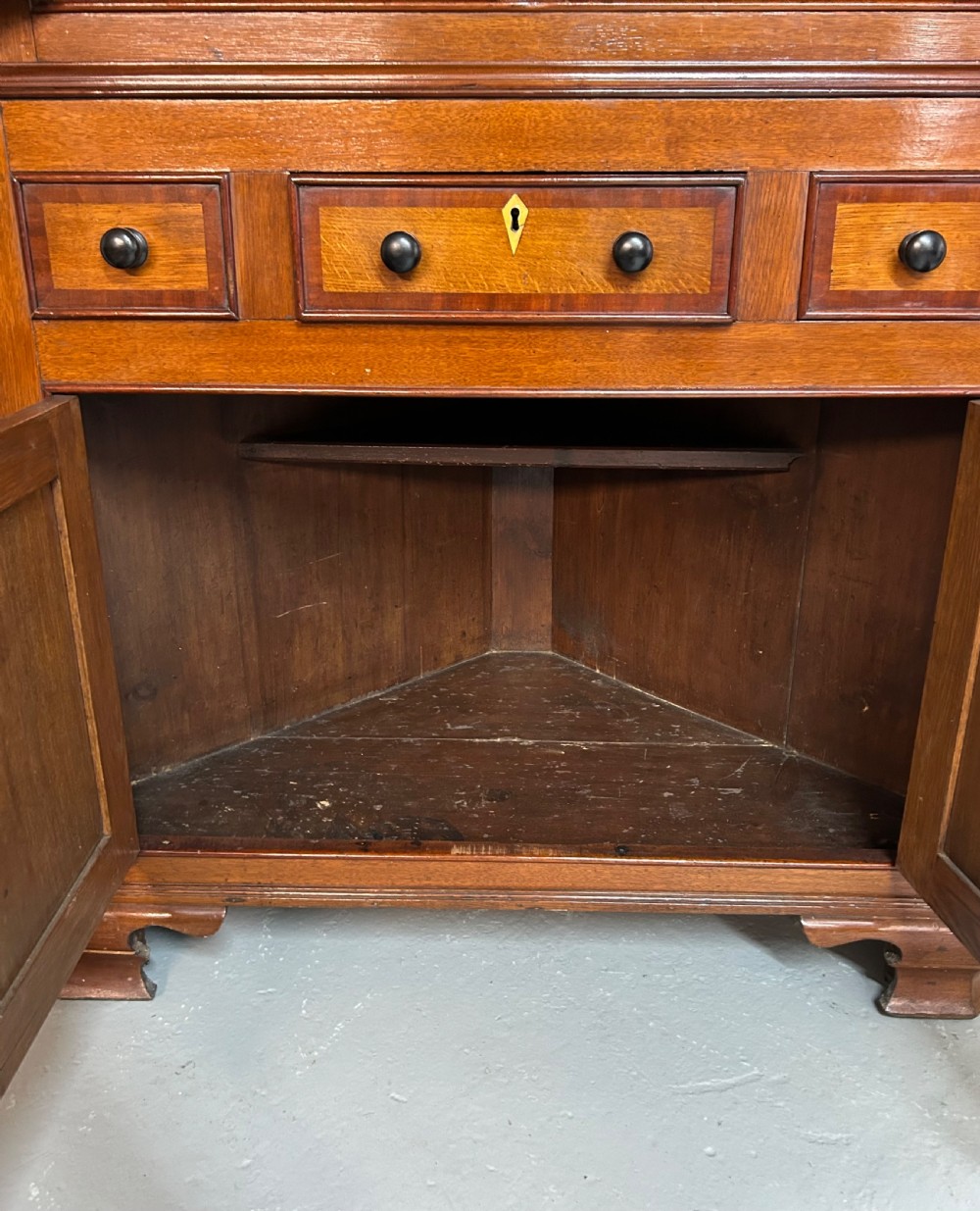A tall freestanding antique Welsh oak corner cabinet with upper leaded glass doors, turned pendant drop mouldings, middle drawers, and lower panelled doors. View VIII