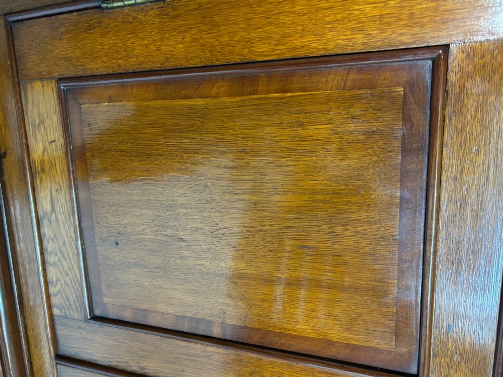 A tall freestanding antique Welsh oak corner cabinet with upper leaded glass doors, turned pendant drop mouldings, middle drawers, and lower panelled doors. View X