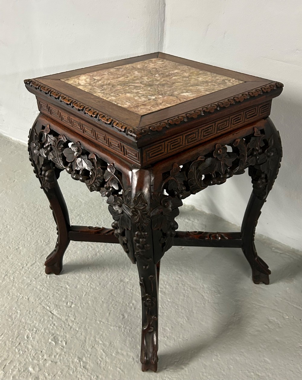 A square carved dark hardwood side table featuring an inset variegated marble top, pierced floral apron, and curved legs with an X-stretcher. View II