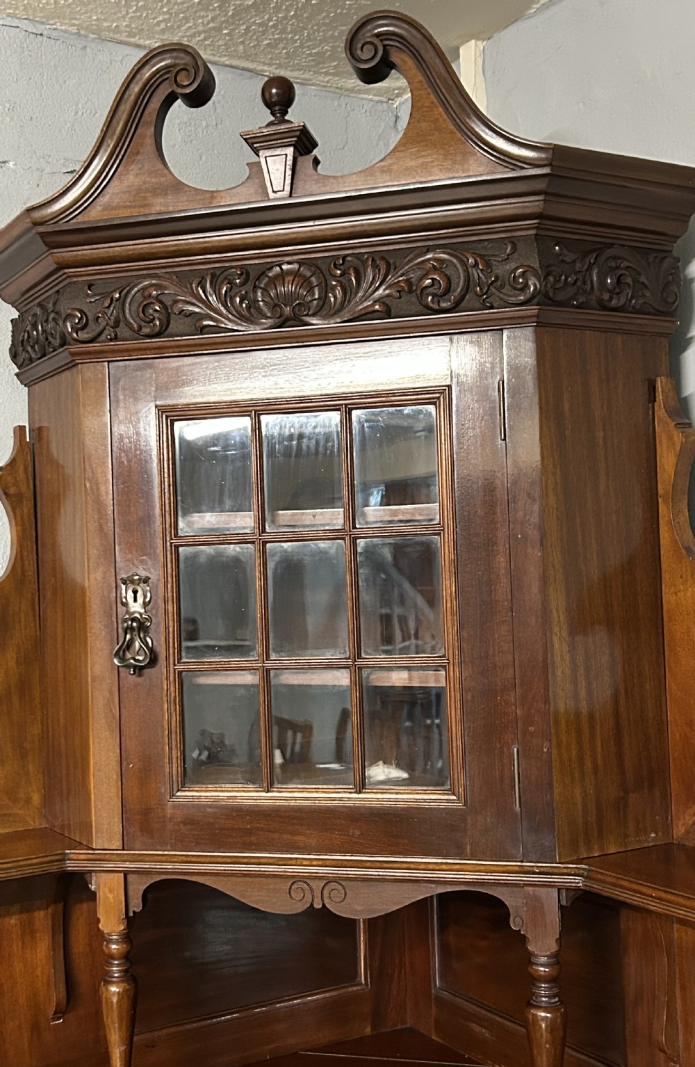 A large Victorian mahogany corner bookcase featuring open shelves along one section, a central panelled door cupboard, and an elevated glazed corner cabinet topped with a swan-neck pediment. View III