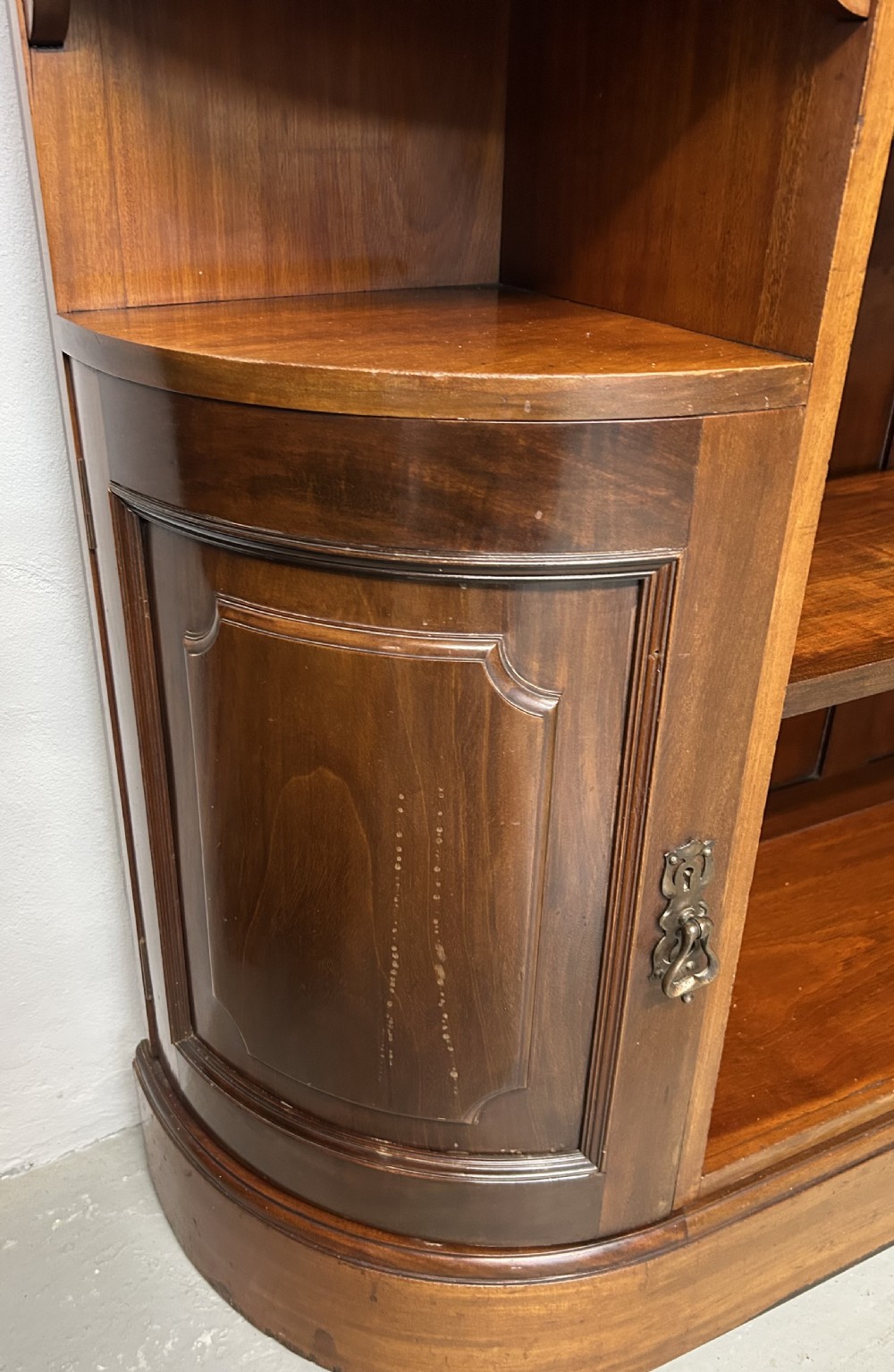 A large Victorian mahogany corner bookcase featuring open shelves along one section, a central panelled door cupboard, and an elevated glazed corner cabinet topped with a swan-neck pediment. View IX
