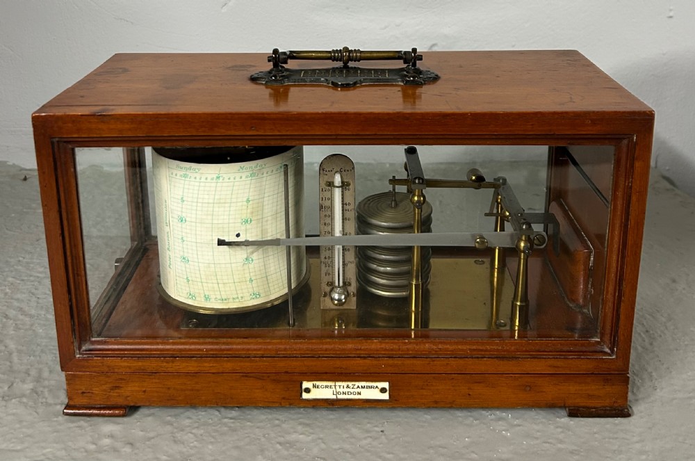 An antique oak and glass barograph featuring a revolving chart drum, internal brass mechanism, thermometer scale, and a brass carrying handle on top.