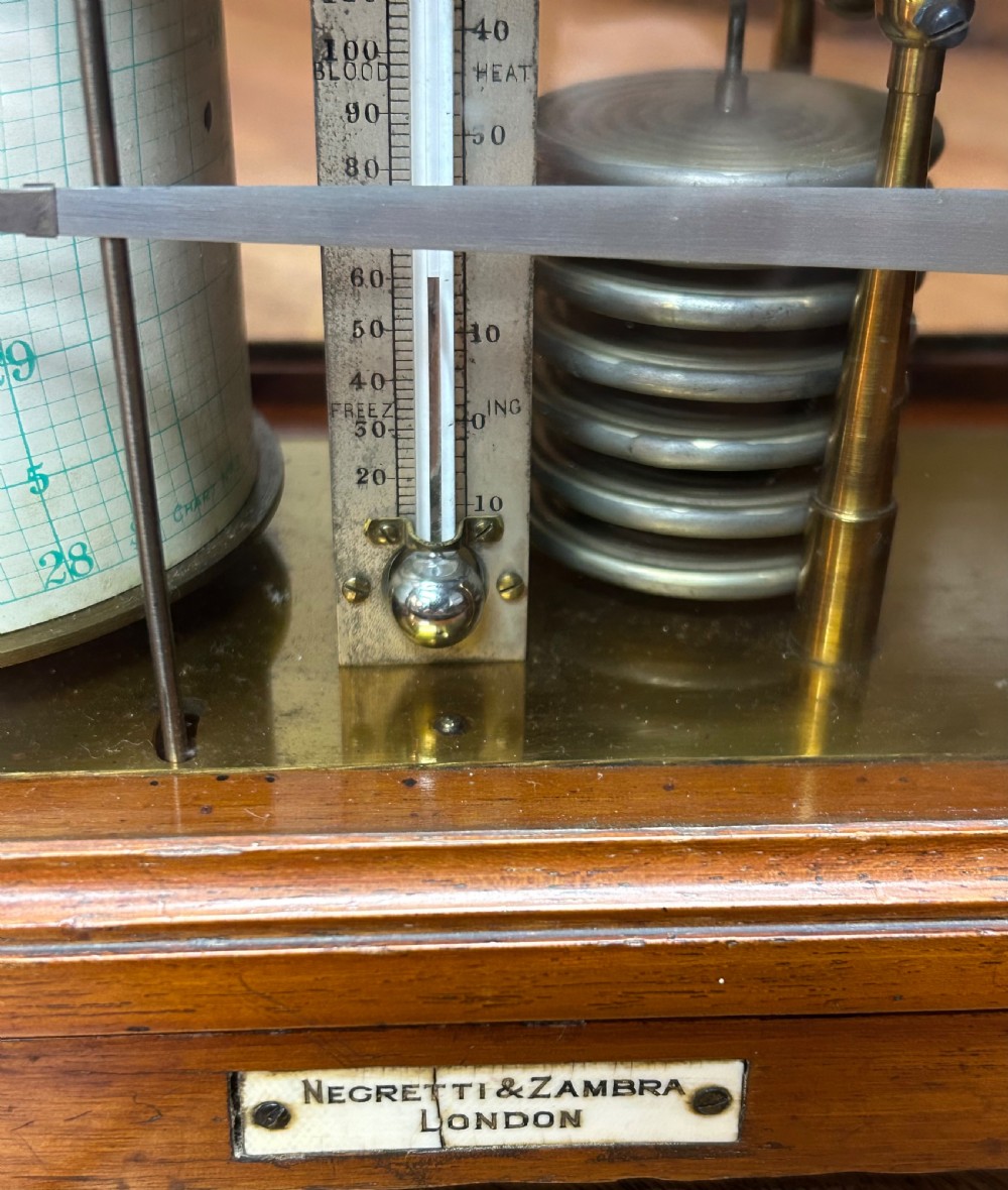 An antique oak and glass barograph featuring a revolving chart drum, internal brass mechanism, thermometer scale, and a brass carrying handle on top. View VI