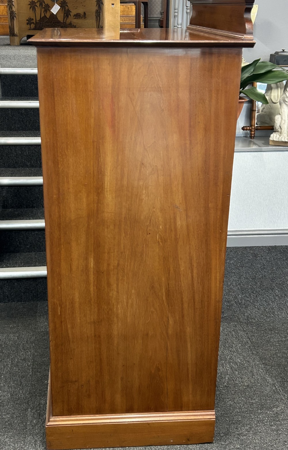 A tall mahogany gentlemans chest featuring five left-hand drawers beside a panelled cupboard door, over a wide base drawer with brass handles. View VII