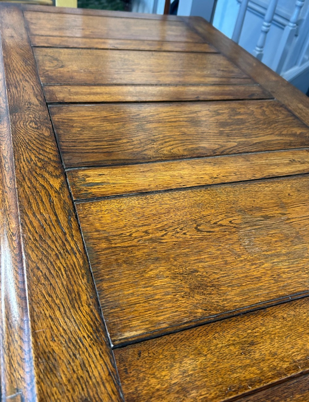 A 19th-century warm brown oak mule chest featuring a four-panel front, hinged top lid, and two lower drawers with brass swan-neck handles. View V