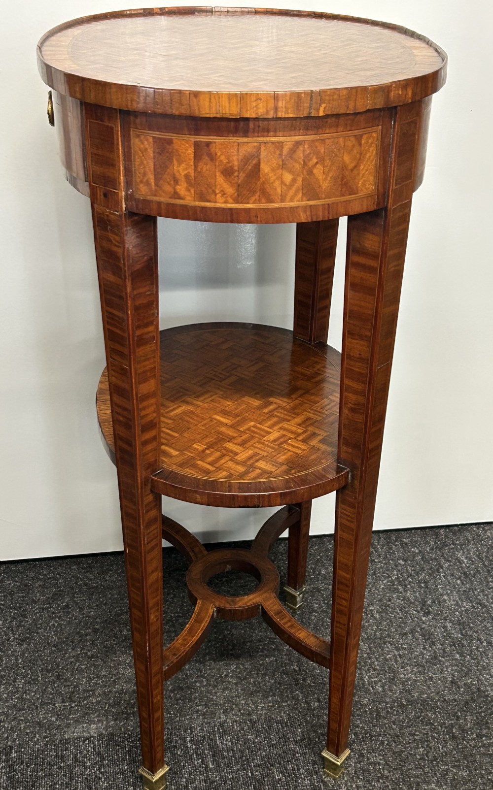 A French-style kingswood side table featuring a geometric parquetry top, a small drawer with a brass ring pull, a lower undershelf, and curved cross-stretchers. View V