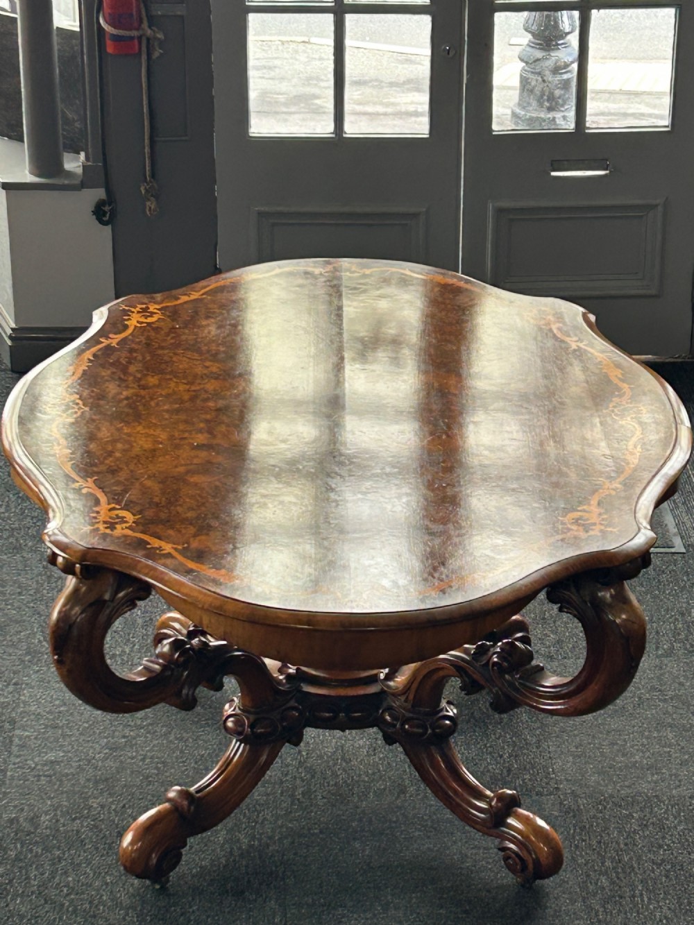 A Victorian burr walnut centre table featuring a serpentine shaped top with marquetry inlay and carved cabriole legs. View V