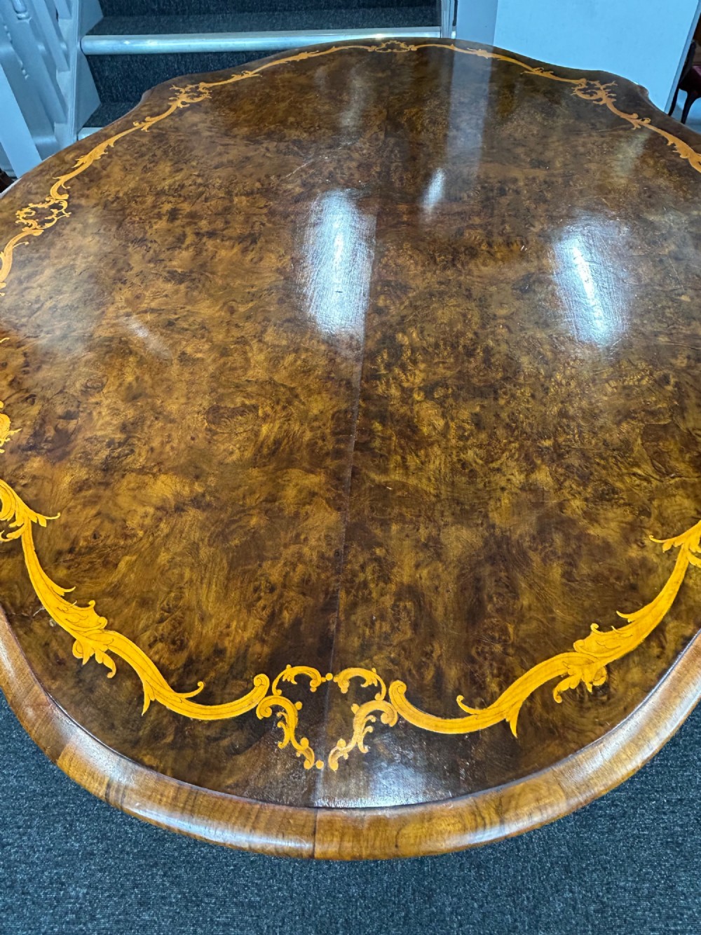 A Victorian burr walnut centre table featuring a serpentine shaped top with marquetry inlay and carved cabriole legs. View VI