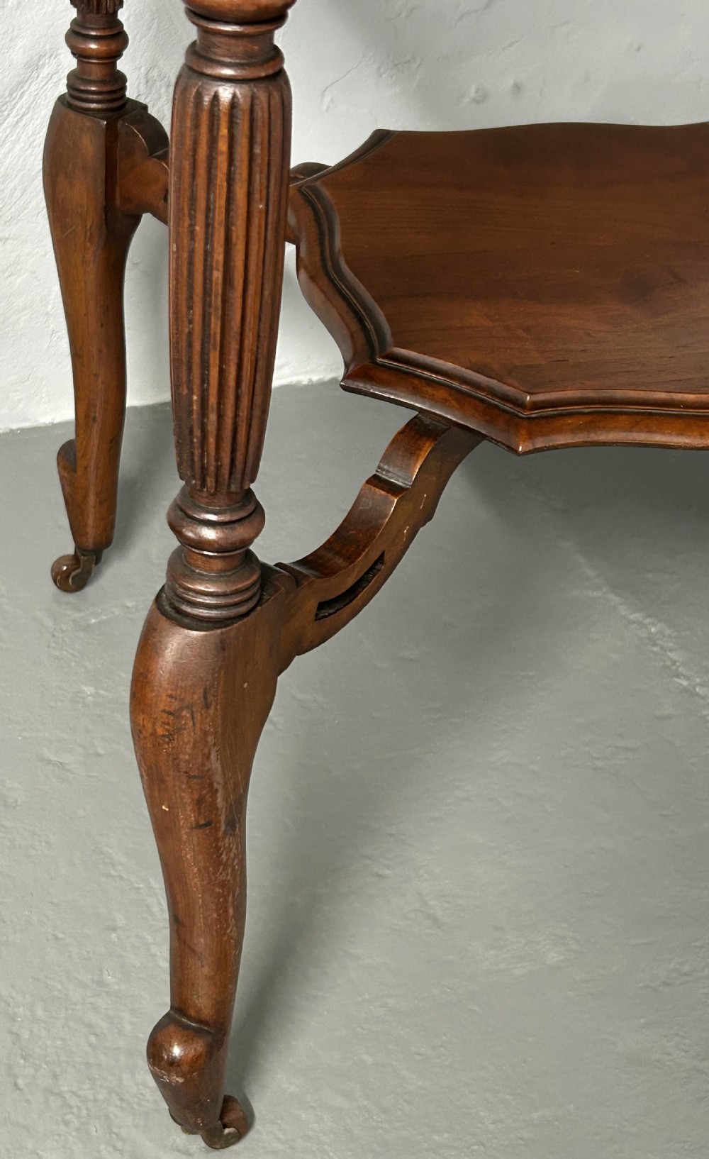 An Edwardian walnut occasional table with a shaped octagonal top, lower tier shelf, turned legs, and small castors. View III
