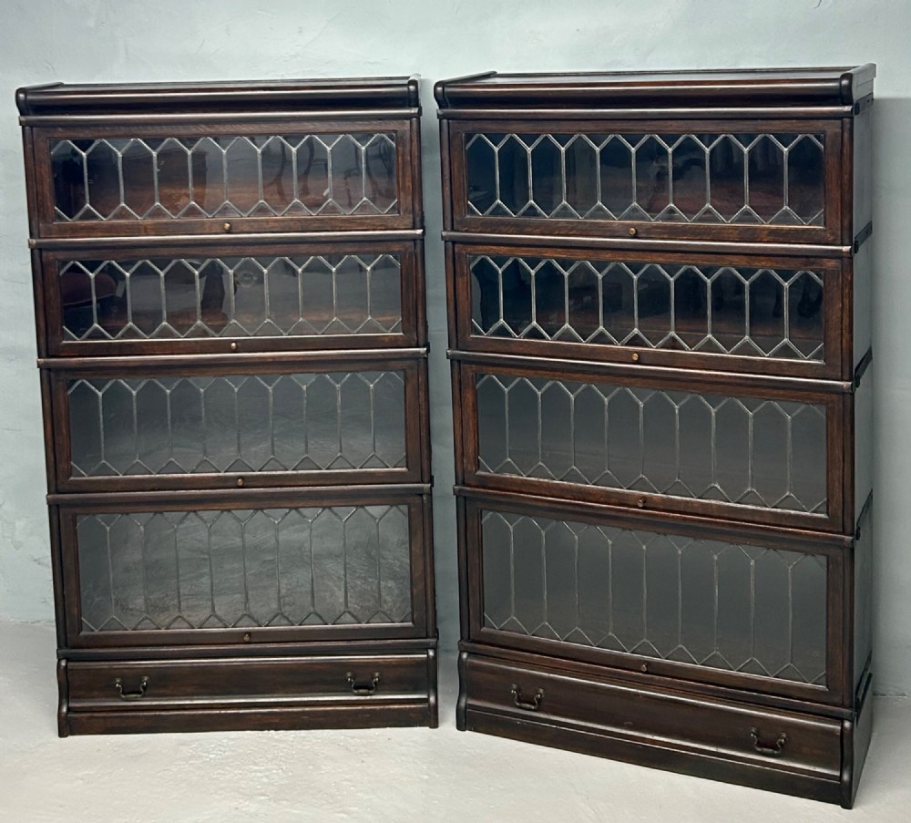 A pair of dark oak Globe Wernicke sectional bookcases featuring four leaded glass door compartments and a base drawer each. View II