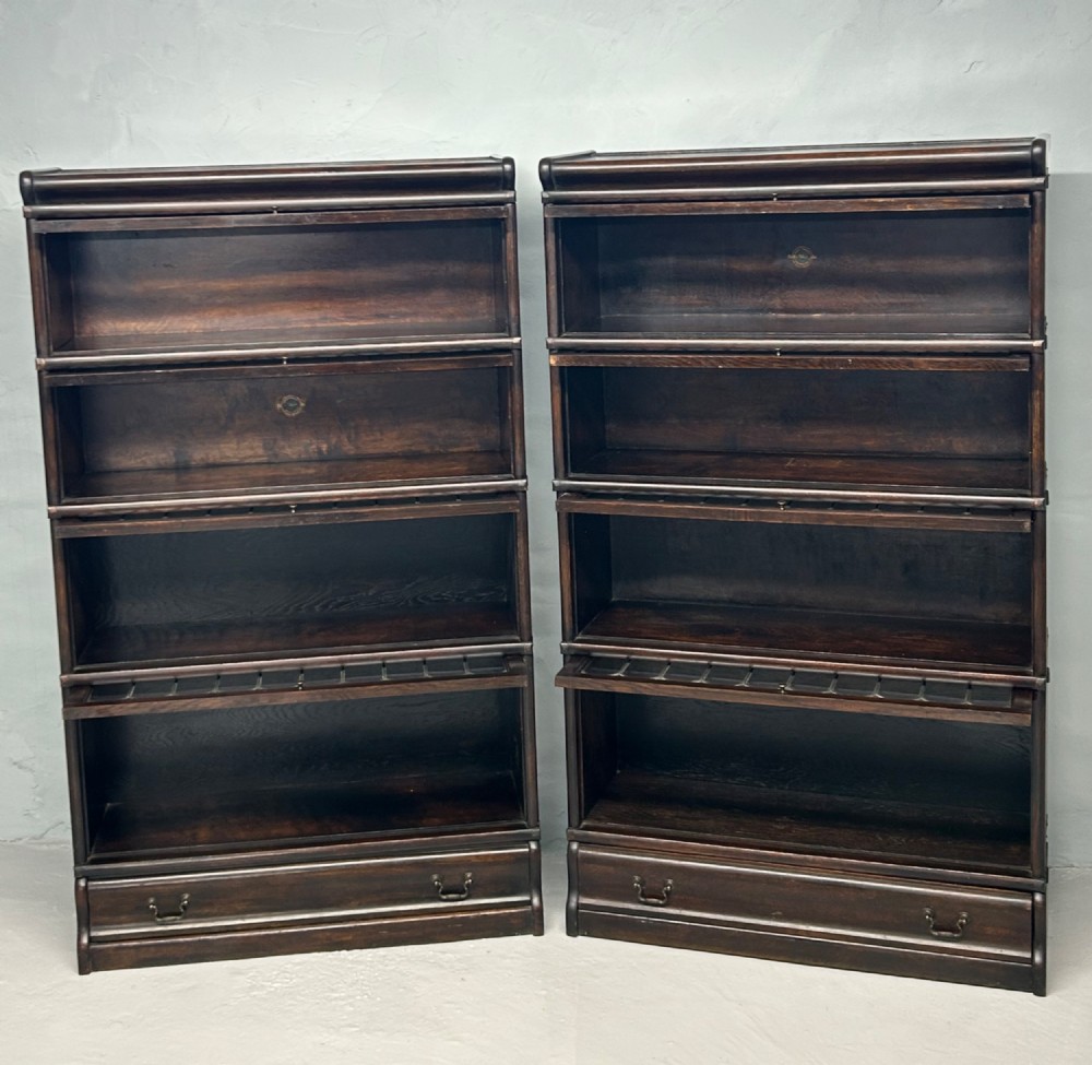 A pair of dark oak Globe Wernicke sectional bookcases featuring four leaded glass door compartments and a base drawer each. View IV