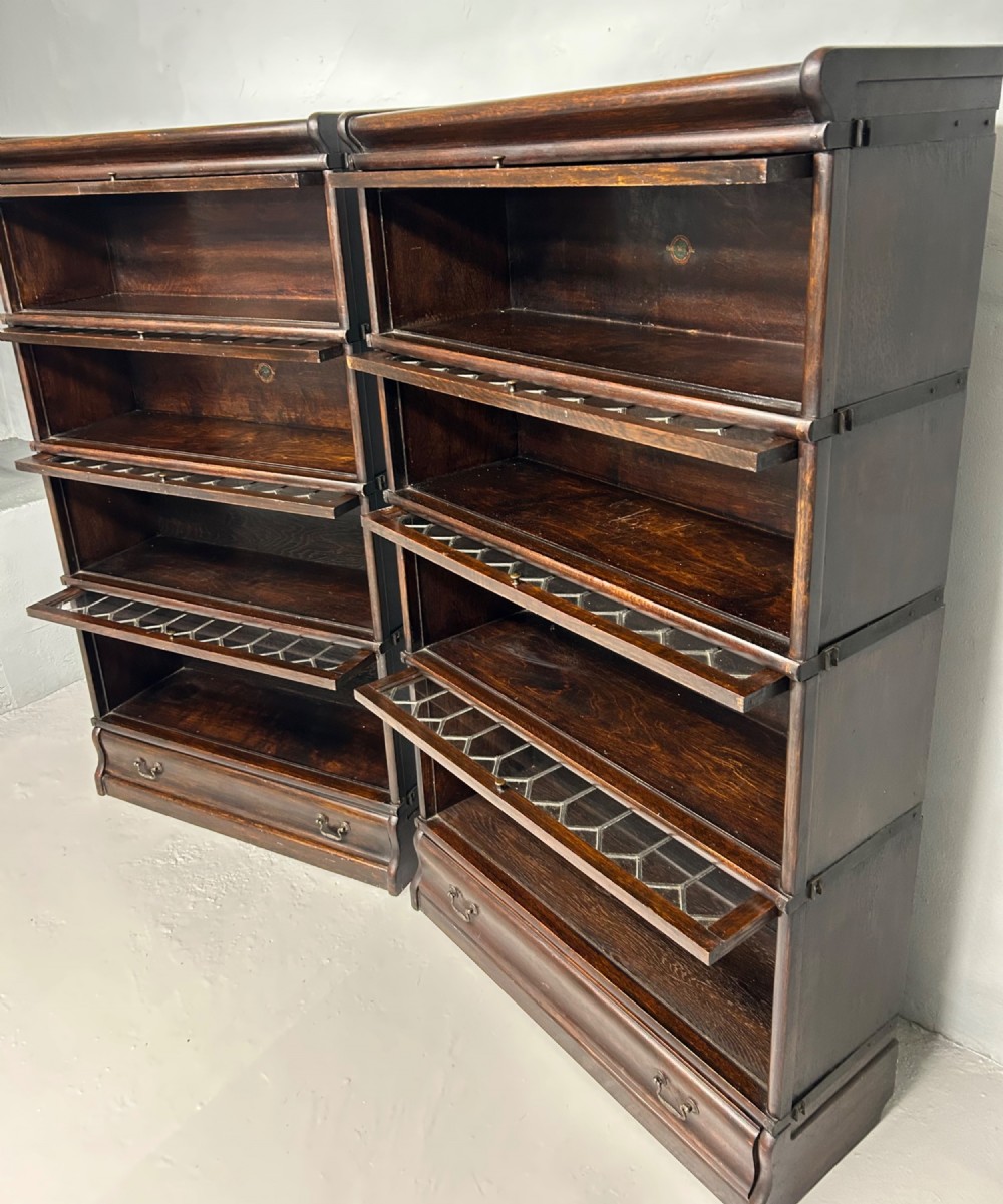 A pair of dark oak Globe Wernicke sectional bookcases featuring four leaded glass door compartments and a base drawer each. View V