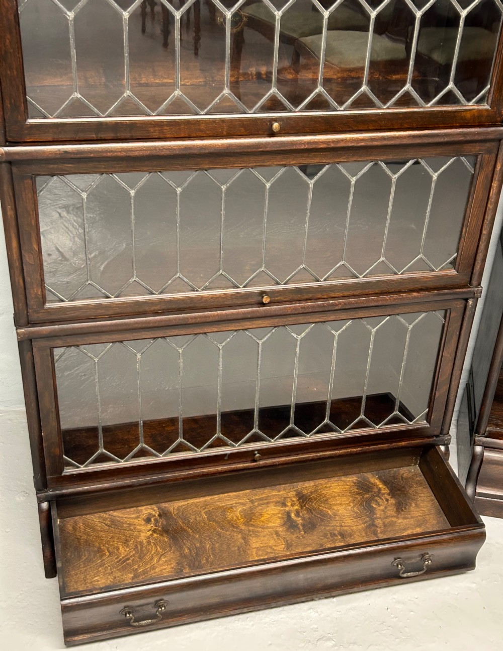 A pair of dark oak Globe Wernicke sectional bookcases featuring four leaded glass door compartments and a base drawer each. View VI