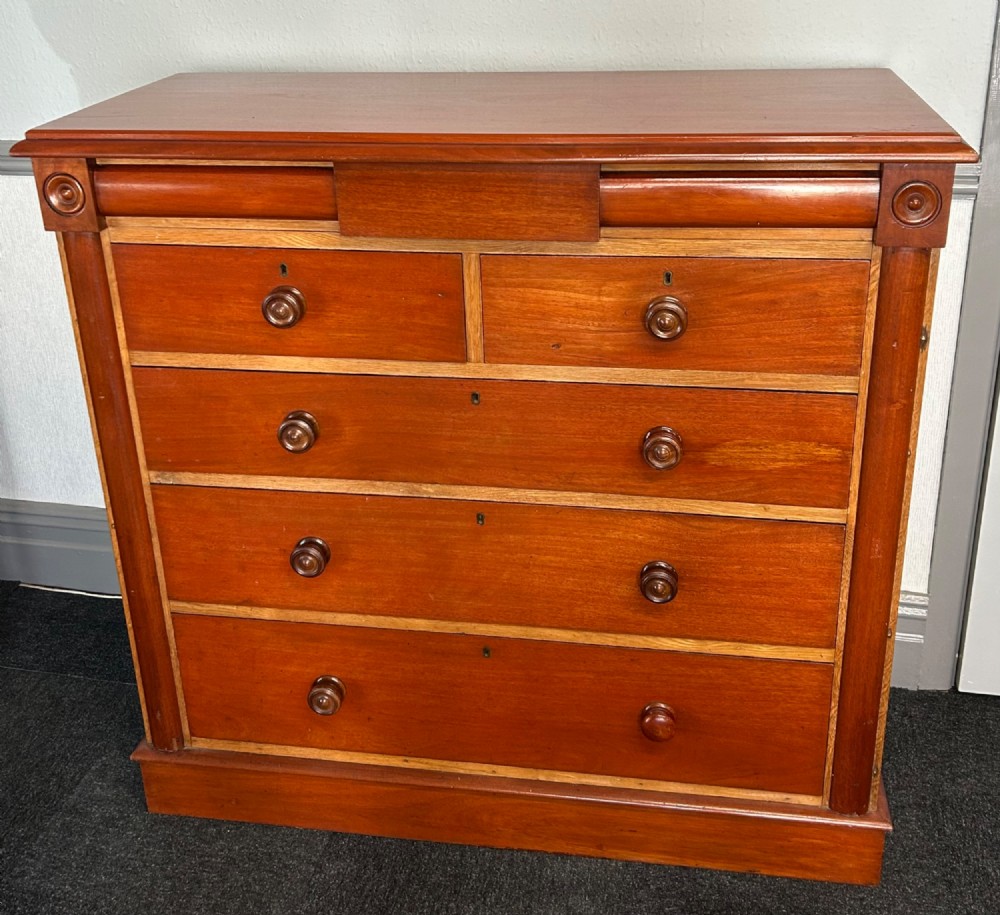A Victorian mahogany and oak chest of drawers featuring two short drawers over three long drawers with turned wooden knobs and roundel details.