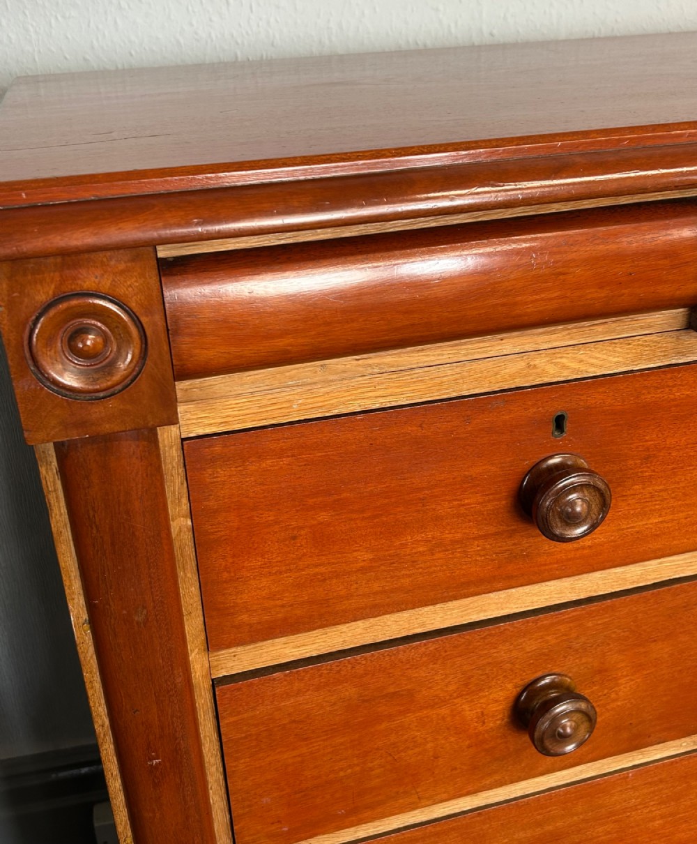 A Victorian mahogany and oak chest of drawers featuring two short drawers over three long drawers with turned wooden knobs and roundel details. View IV