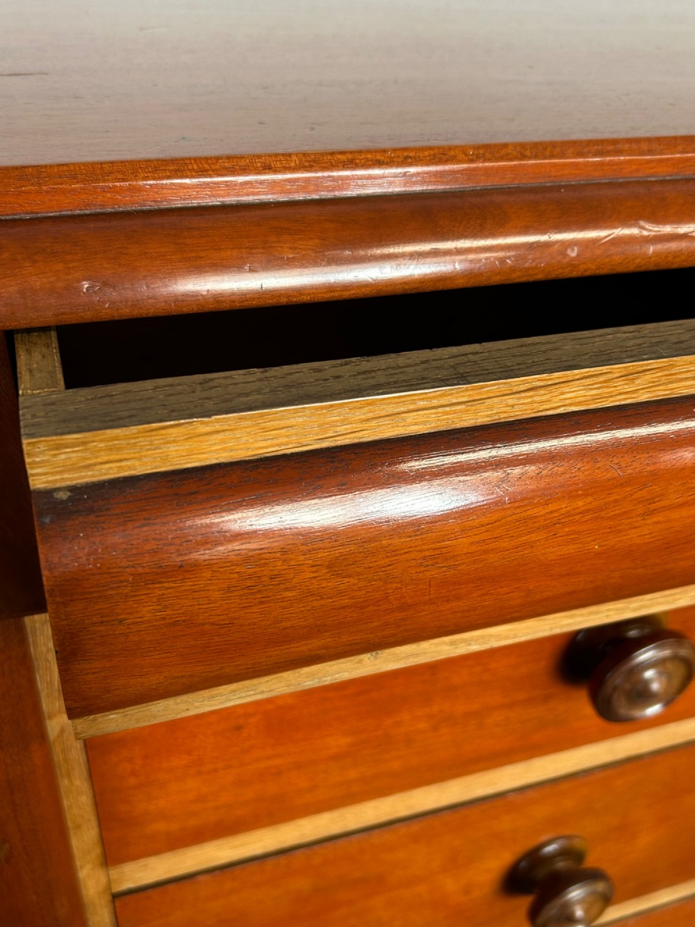 A Victorian mahogany and oak chest of drawers featuring two short drawers over three long drawers with turned wooden knobs and roundel details. View V