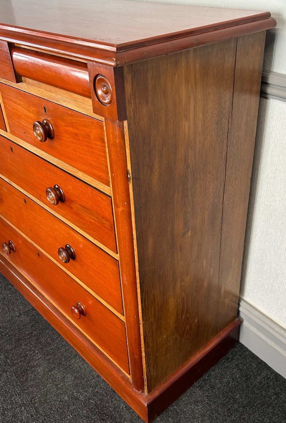 A Victorian mahogany and oak chest of drawers featuring two short drawers over three long drawers with turned wooden knobs and roundel details. View VI