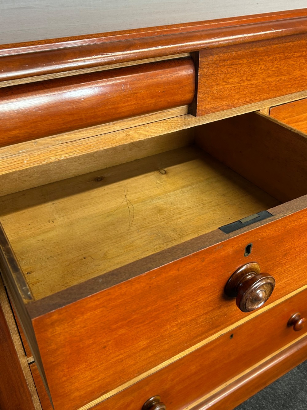 A Victorian mahogany and oak chest of drawers featuring two short drawers over three long drawers with turned wooden knobs and roundel details. View X