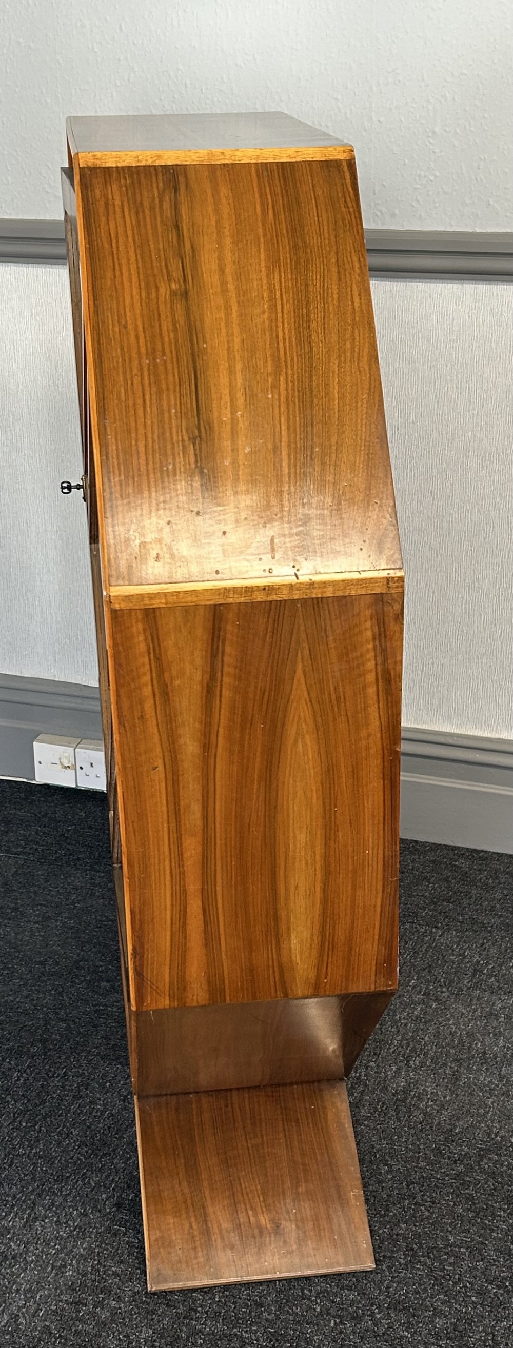 An octagonal Art Deco walnut display cabinet featuring a central glazed door with diagonal glazing bars and glass interior shelves on a flared plinth base. View III