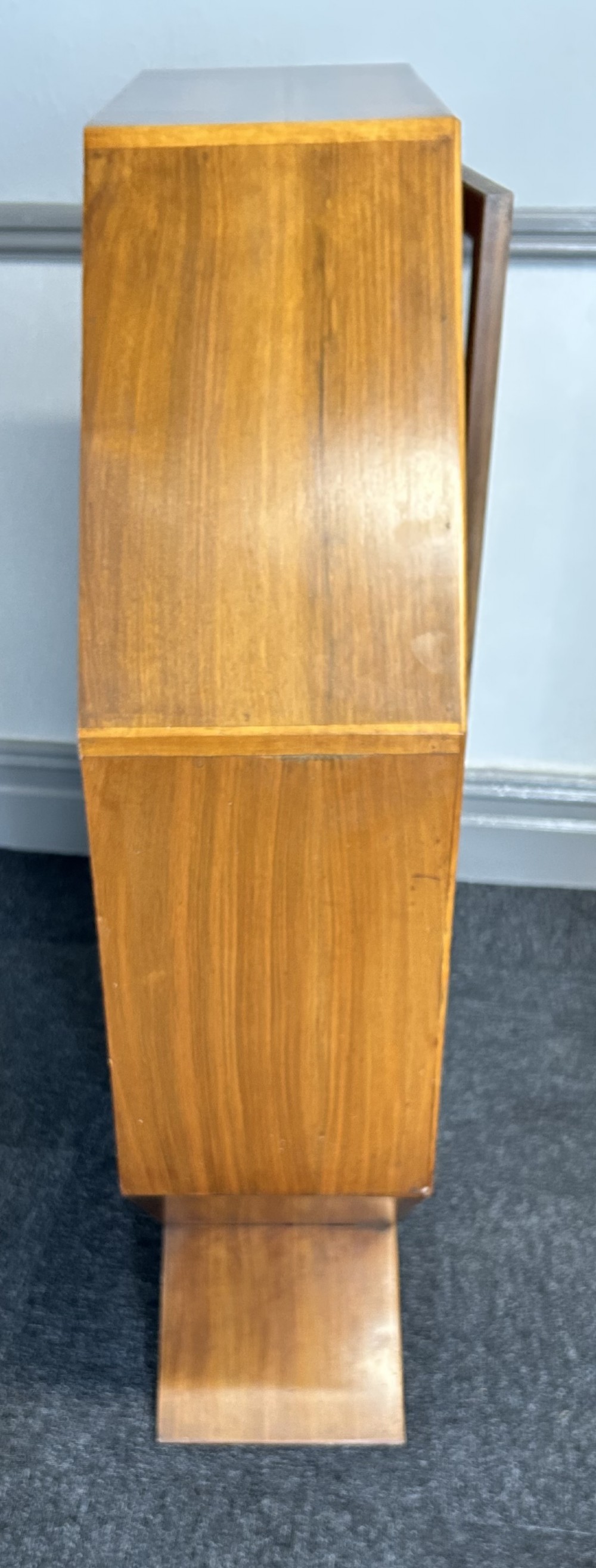 An octagonal Art Deco walnut display cabinet featuring a central glazed door with diagonal glazing bars and glass interior shelves on a flared plinth base. View IV