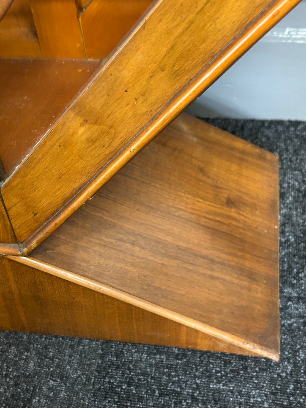 An octagonal Art Deco walnut display cabinet featuring a central glazed door with diagonal glazing bars and glass interior shelves on a flared plinth base. View V