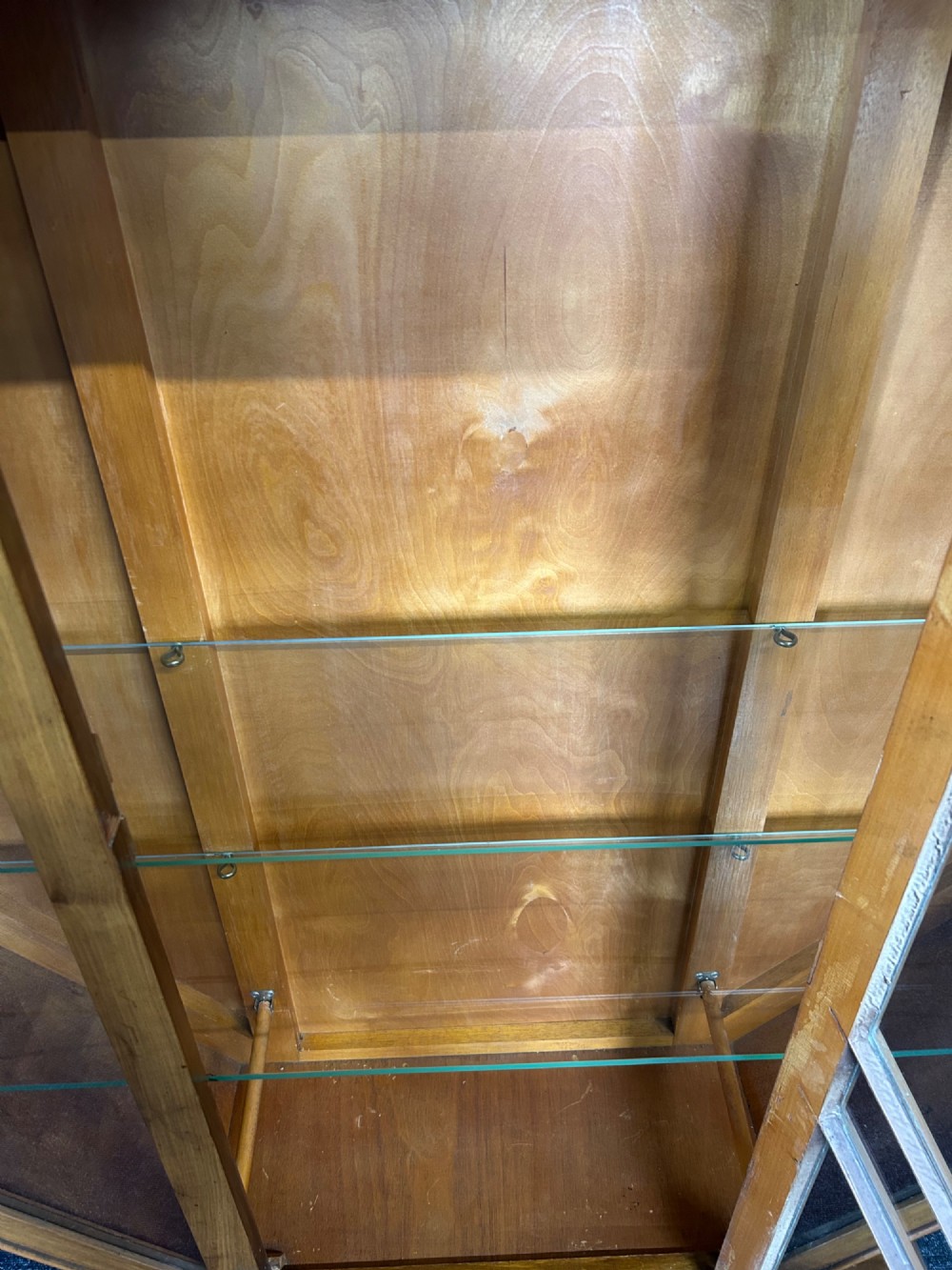 An octagonal Art Deco walnut display cabinet featuring a central glazed door with diagonal glazing bars and glass interior shelves on a flared plinth base. View VI