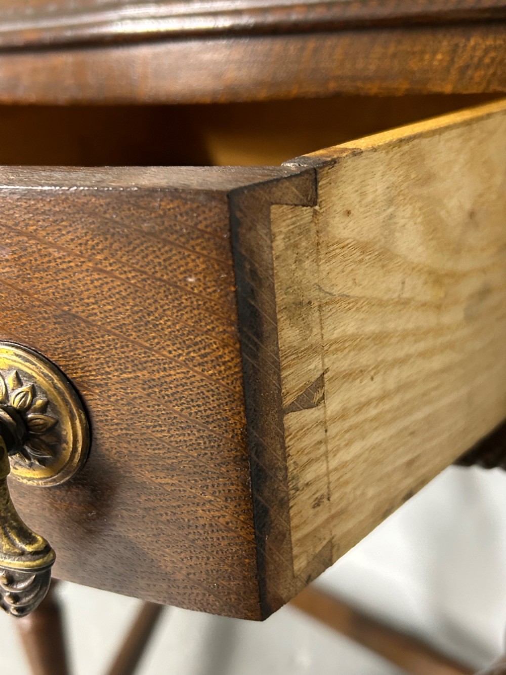 A 1920s dark oak demi-lune console table featuring a carved strapwork drawer, turned front legs, and a low gallery back. View V