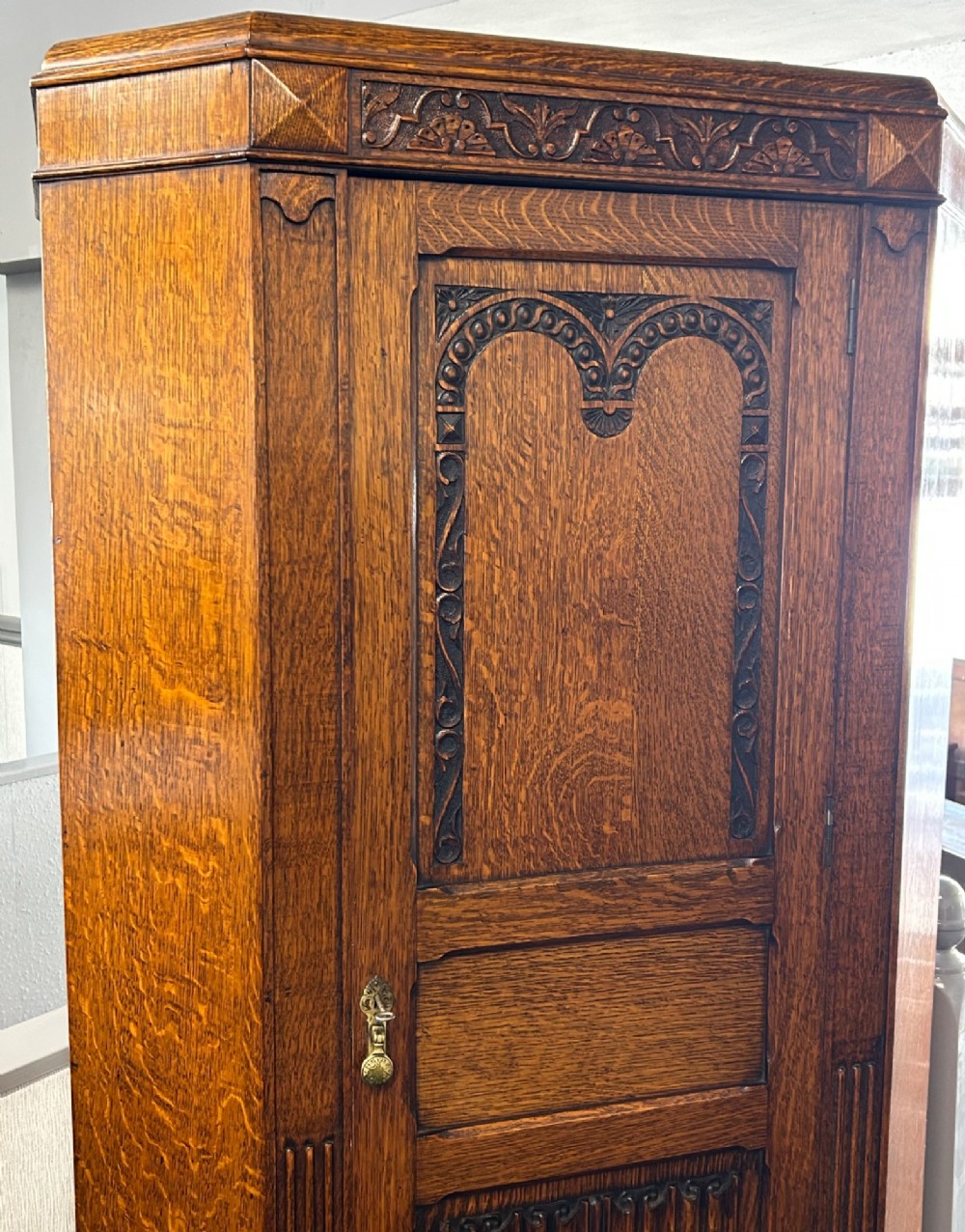 A tall 1920s solid oak hall robe featuring a single door with carved arcading and linenfold panelling, canted sides, and turned feet. View II