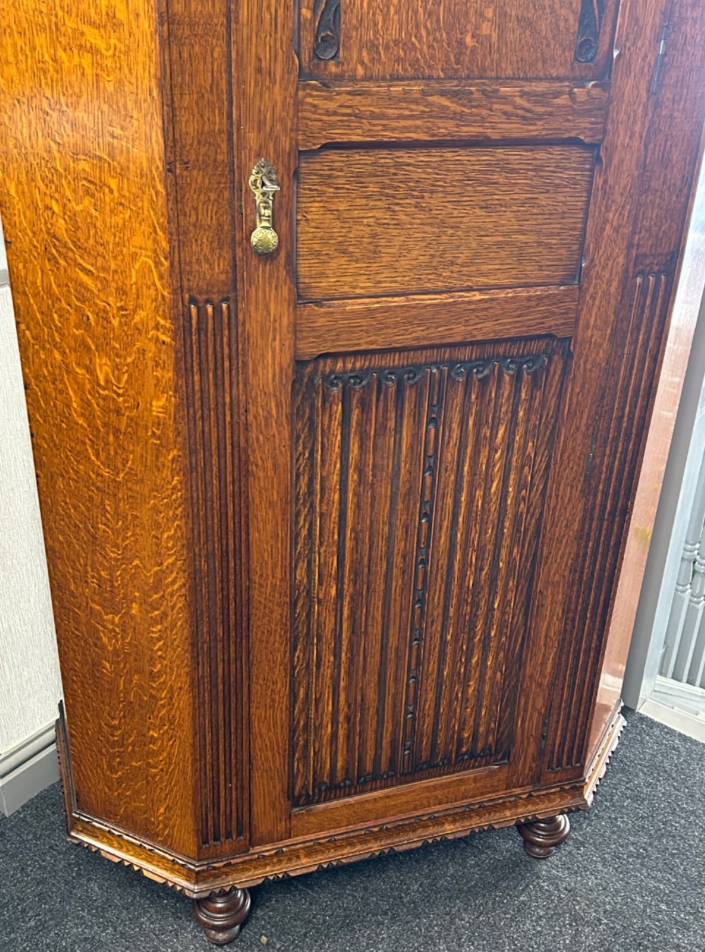A tall 1920s solid oak hall robe featuring a single door with carved arcading and linenfold panelling, canted sides, and turned feet. View III