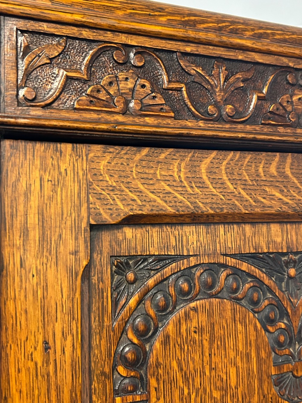 A tall 1920s solid oak hall robe featuring a single door with carved arcading and linenfold panelling, canted sides, and turned feet. View IV