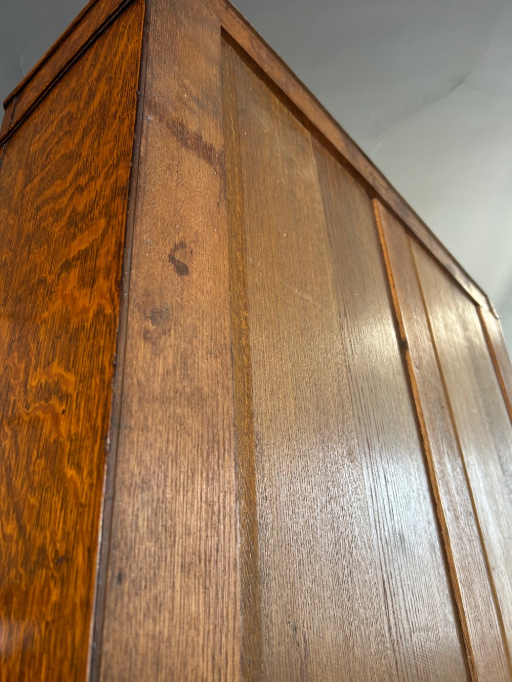 A tall 1920s solid oak hall robe featuring a single door with carved arcading and linenfold panelling, canted sides, and turned feet. View VIII