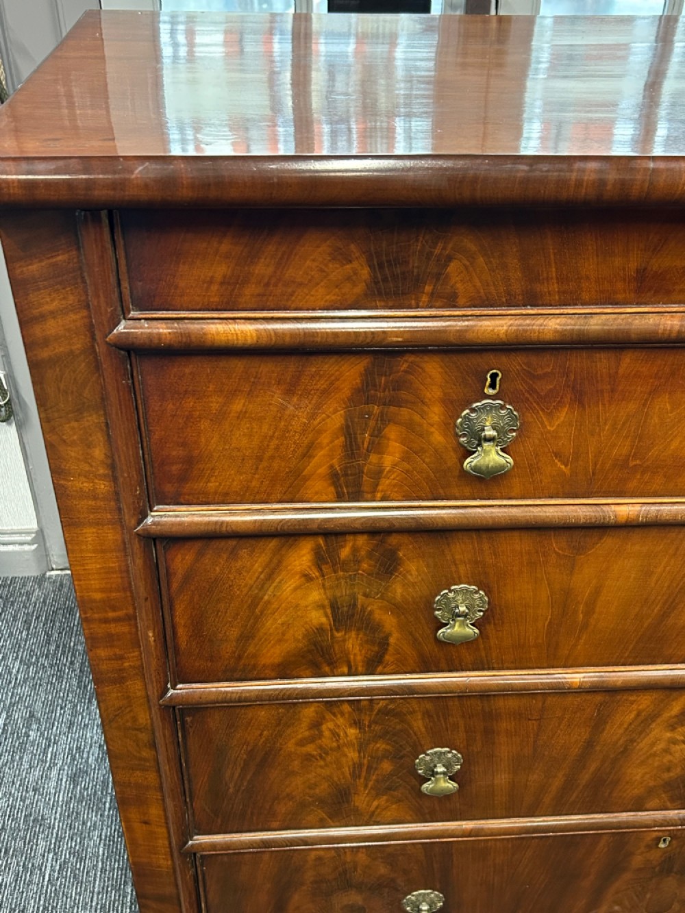 A nineteenth-century Victorian flame mahogany chest of drawers featuring two short drawers over three long graduated drawers with decorative brass drop handles and bun feet. View II