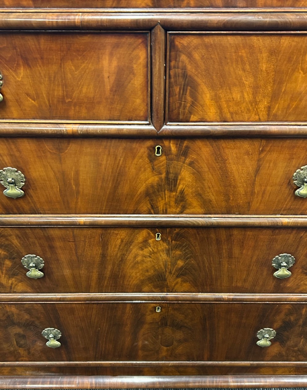 A nineteenth-century Victorian flame mahogany chest of drawers featuring two short drawers over three long graduated drawers with decorative brass drop handles and bun feet. View VI