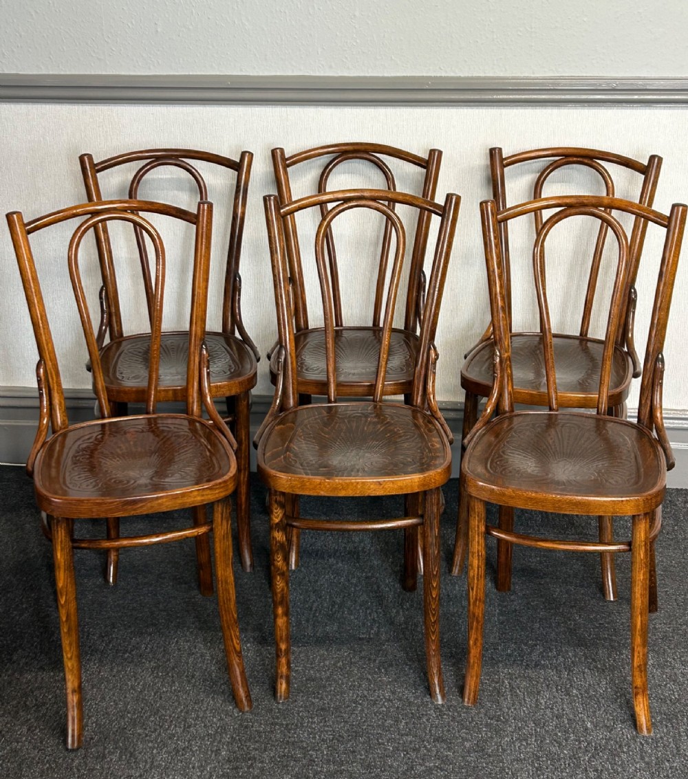 A set of six dark brown bentwood dining chairs featuring curved backrests and relief patterned wooden seats.