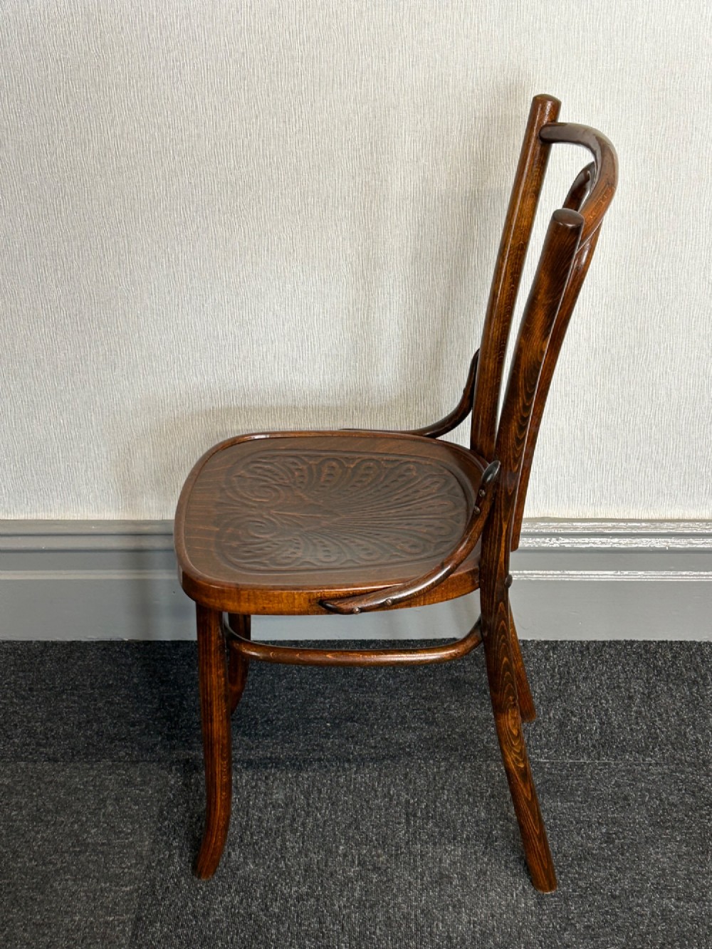A set of six dark brown bentwood dining chairs featuring curved backrests and relief patterned wooden seats. View III