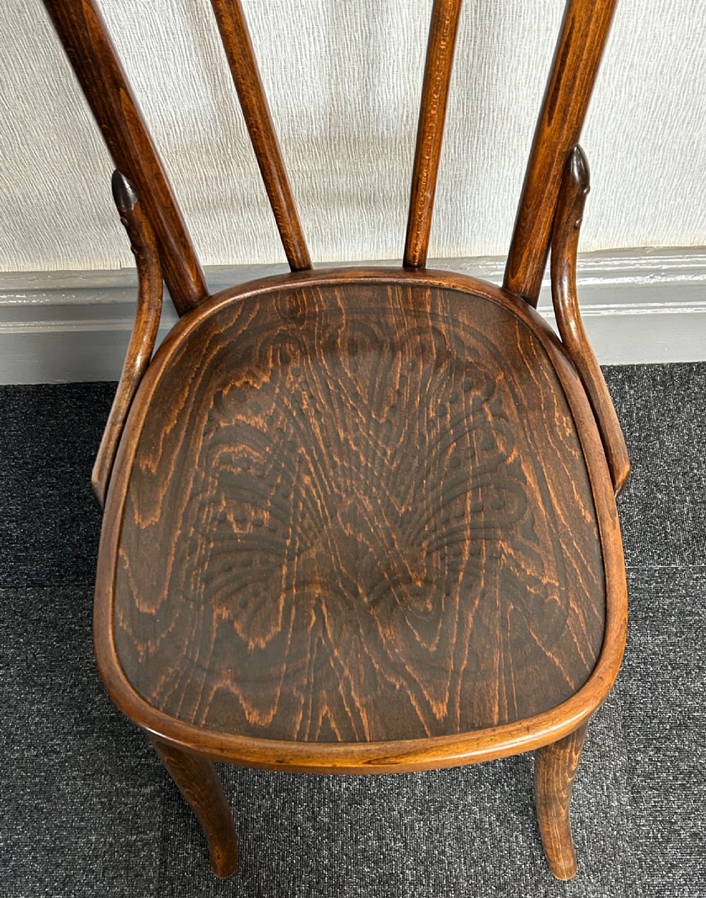 A set of six dark brown bentwood dining chairs featuring curved backrests and relief patterned wooden seats. View V